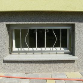 Fenstergitter an einem Kellerfenster,wo zwei vertikale Streben bauchig sind und das strenge auflockern