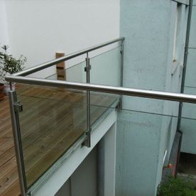 Glasgeländer mit Metallhandlauf an einem Balkon mit Parkettboden